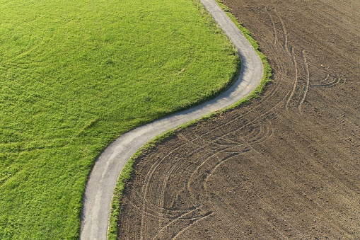 Aerial view of a path between meadow and field.
