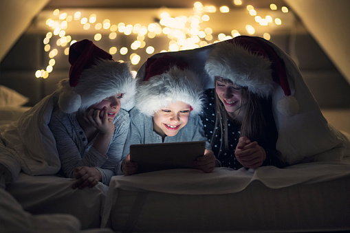 Three kids reading Christmas tales on Christmas Eve. Kids are under the duvet.
Nikon D850