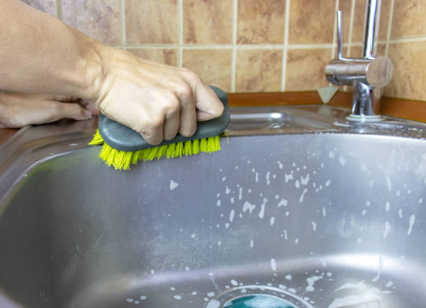 istock Woman's cropped hands washes and cleans a sink with a sponge and brush. 1038700690