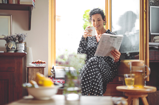 Mature woman is reading the morning newspaper