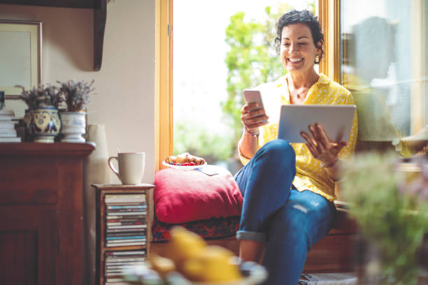 mujer madura es comprar en línea en casa - women computer home interior brown hair fotografías e imágenes de stock