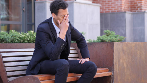 istock Tense African Businessman with Headache Sitting on Bench 1038709626