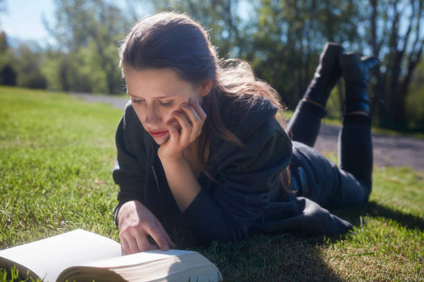 istock Beautiful woman relaxing on the grass with book 1038736170