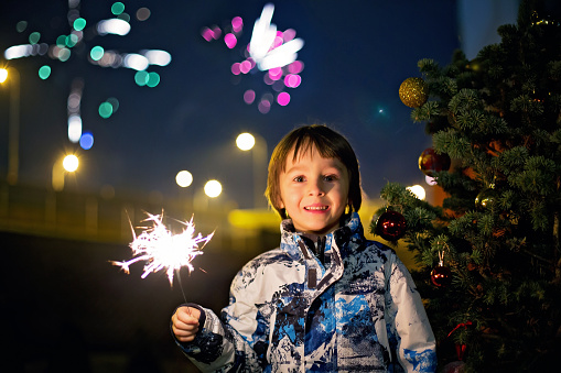 Preschool children, holding sparkler, celebrating new years eve outdoors