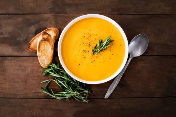 Pumpkin and carrot  Cream soup on  wood rustic  background. Autumn cream-soup in country style. Top view. Copy space"n