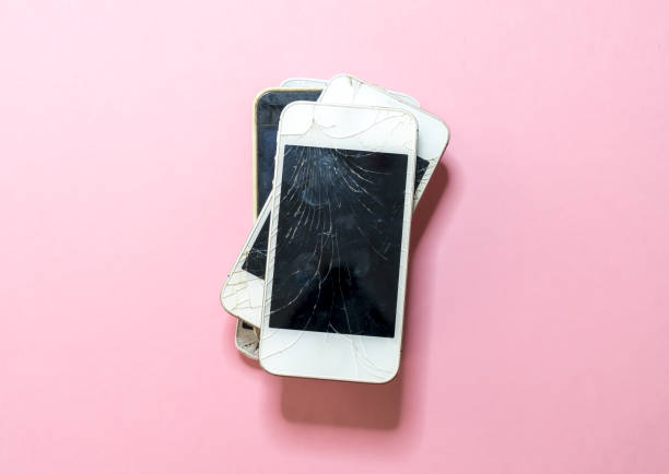 pile of old broken mobile phones with pink background