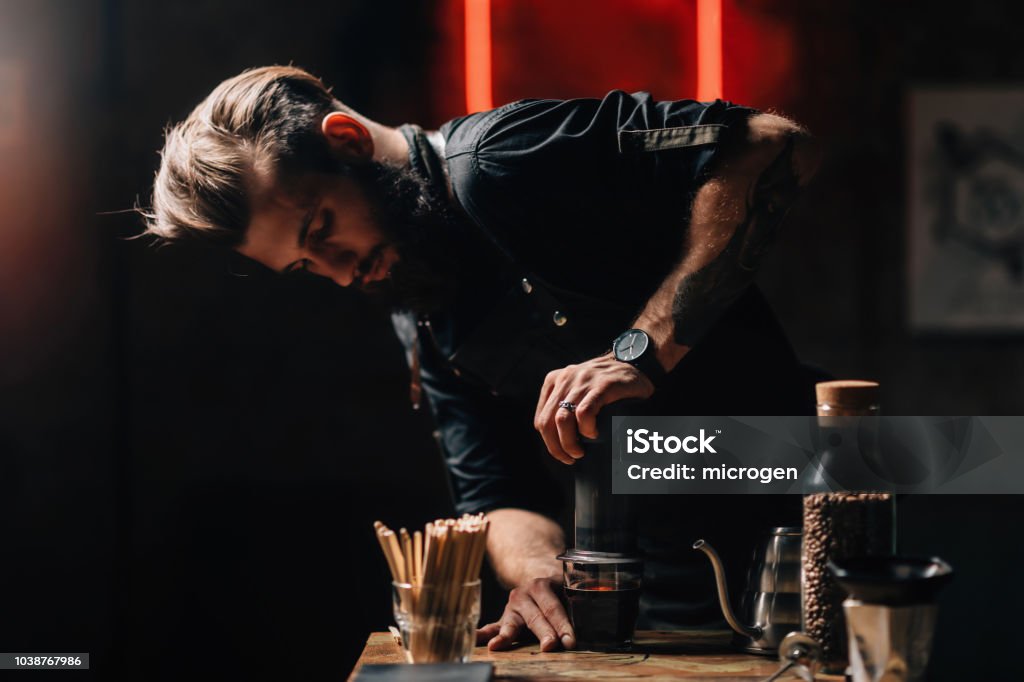 Barista Making Pour Over Air Press Filter Coffee Barista making air press pour over coffee. Barista with tattooed arms wearing dark uniform. Coffee - Drink Stock Photo