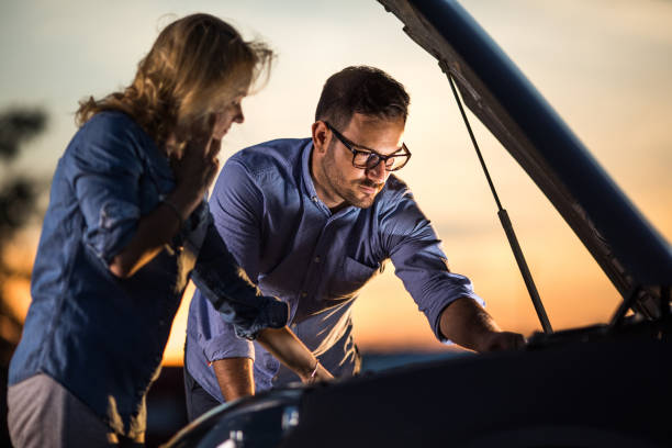 istock Young couple examining their broken car at sunset. 1038773818