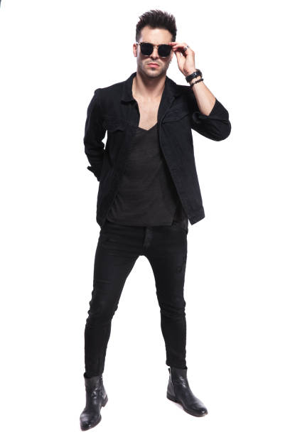 istock cool young man in black clothes arranges sunglasses while standing 1038786932