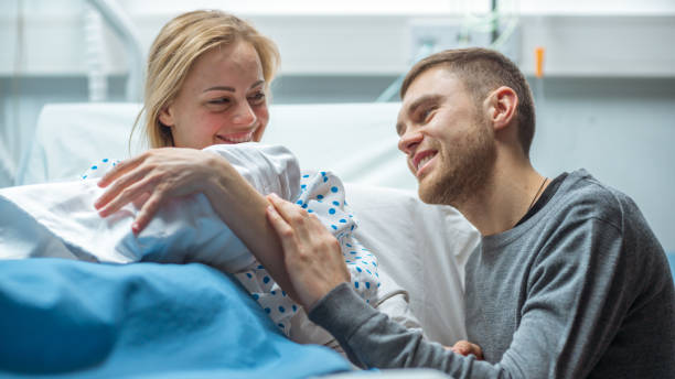 w szpitalu matka posiada noworodka, wspierający ojciec miłością przytula dziecko i żonę. szczęśliwa rodzina w nowoczesnym oddziale porodowym. - male nurse nurse hospital ward hospital zdjęcia i obrazy z banku zdjęć