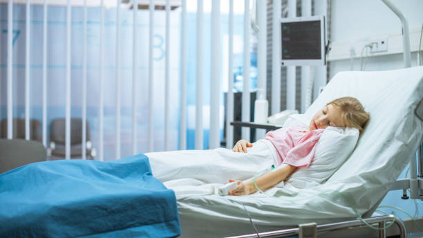 Cute Little Sick Girl Sleeps on a Bed in the Children's Hospital. Modern Pediatric Ward with Top Quality Health Care. Cute Little Sick Girl Sleeps on a Bed in the Children's Hospital. Modern Pediatric Ward with Top Quality Health Care. sick child hospital bed stock pictures, royalty-free photos & images