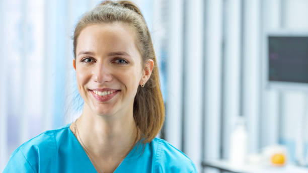 porträtaufnahme von schöne junge krankenschwester charmant lächeln in die kamera. professionelle und zuverlässige menschen bei der arbeit. im hintergrund moderne krankenstation. - charmingly stock-fotos und bilder