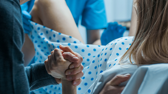 Emergencia en el Hospital: mujer dando a luz, el marido tiene su mano en apoyo, ayudar a obstetras. Entrega moderna sala con parteras profesionales. photo