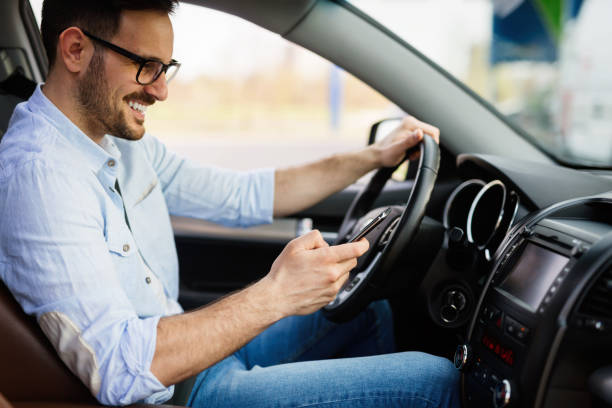 uomo che guarda il cellulare mentre guida - driving text messaging accident danger foto e immagini stock