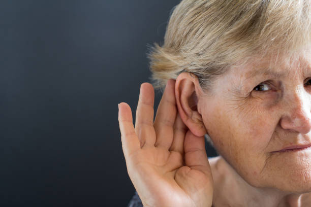 istock Elderly woman with hearing loss on grey background. Age related health problem. 1038830326
