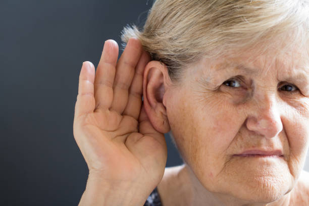 istock Elderly woman with hearing loss on grey background. Age related health problem. 1038831532