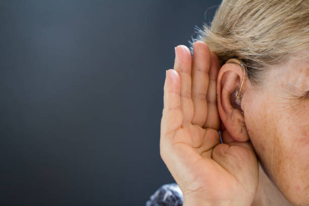 istock Elderly woman with hearing loss on grey background. Age related health problem. 1038833236