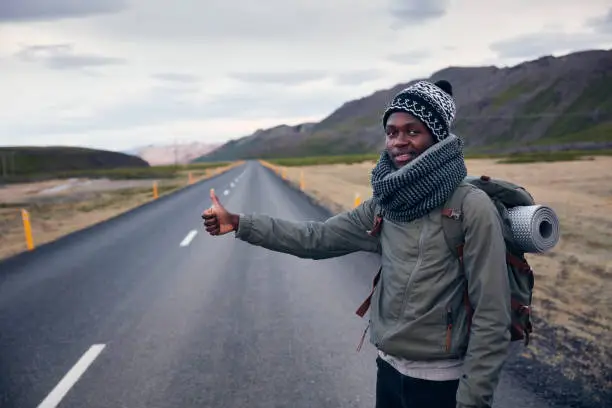 Mountain landscape. Young african ethnicity man staying on roadside