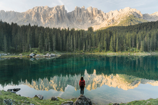 Mujer de pie y mirando el Lago di Carezza en Dolomitas photo