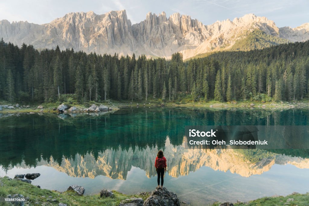 Donna in piedi e guardando il Lago di Carezza nelle Dolomiti - Foto stock royalty-free di Natura