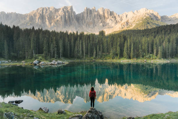 vrouw permanent en kijken naar lago di carezza in dolomieten - zomer fotos stockfoto's en -beelden