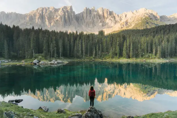 Young Caucasian woman standing and looking at  Lago di Carezza in Dolomites