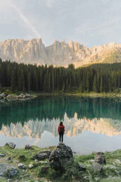 donna in piedi e guardando il lago di carezza nelle dolomiti - mountain austria european alps landscape foto e immagini stock