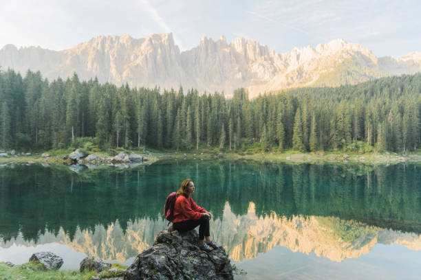 mulher de pé e olhando para o lago di carezza nas dolomitas - latemar mountain range - fotografias e filmes do acervo