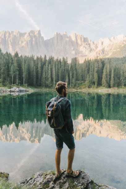 homem de pé e olhando para o lago di carezza nas dolomitas - travel vertical tourist switzerland - fotografias e filmes do acervo