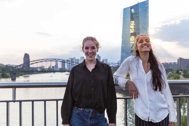 Young Women Posing and Smiling on City Bridge Over River