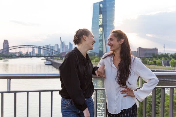 istock Girlfriends Standing on City Bridge Over River Looking at Each Other and Laughing 2 1038879542