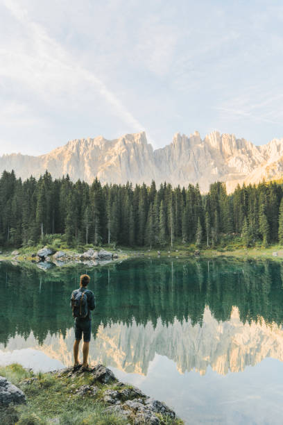 mann stehend und mit blick auf den lago di carezza in dolomiten - latemar mountain range stock-fotos und bilder