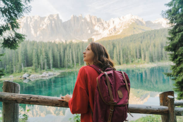 donna in piedi e guardando il lago di carezza nelle dolomiti - latemar mountain range foto e immagini stock