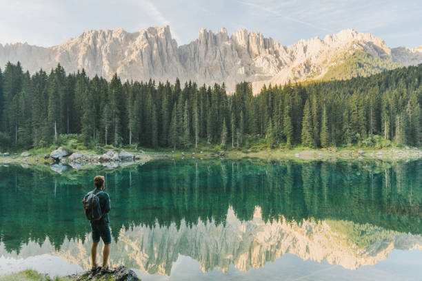 man standing and looking at  lago di carezza in dolomites - switzerland lake mountain landscape imagens e fotografias de stock