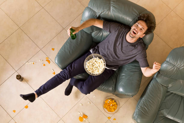 top view of man with beer and chips and popcorn watching tv at home - routine foods and drinks clothing household equipment imagens e fotografias de stock