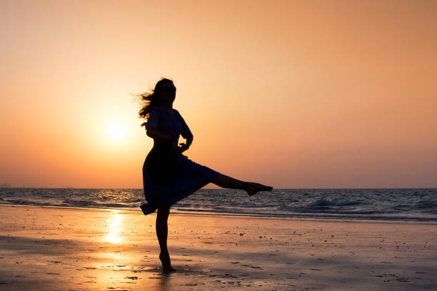 istock Girl dancing on the beach at sunset 1038908848