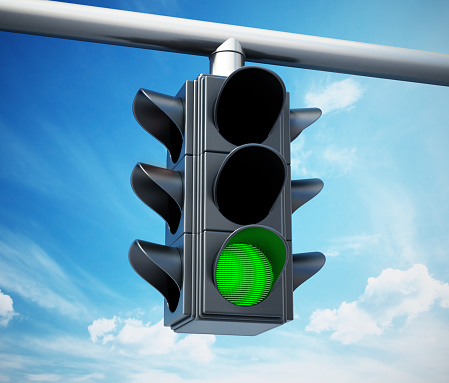 Green traffic light against blue sky