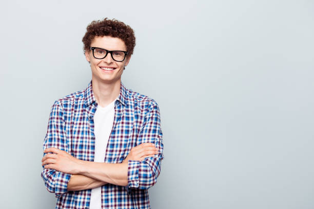 Portrait with copy space and empty place for text with young man Portrait with copy space and empty place for text with young man in glasses with crossed arms looking at camera isolated on light grey background nerd teenager stock pictures, royalty-free photos & images