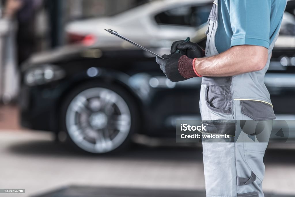 Vehicles Maintenance Work Caucasian Auto Service Worker with Documentation. Vehicles Maintenance Work Auto Repair Shop Stock Photo