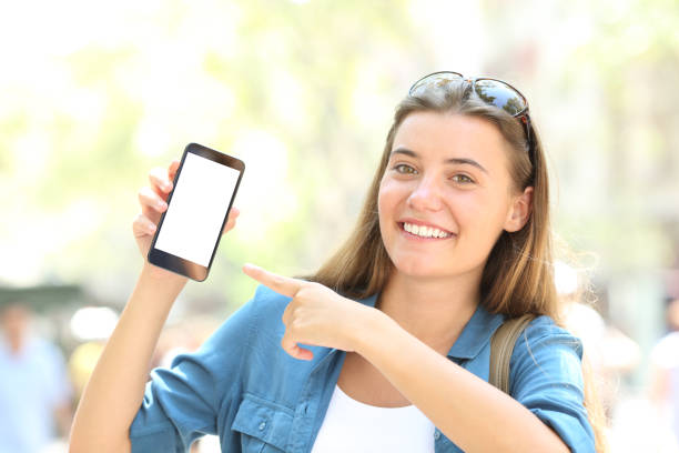 istock Smiley girl pointing to a blank smart phone screen 1038959378