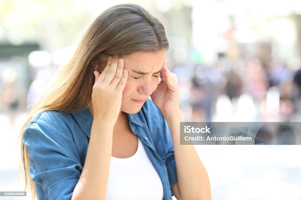 Girl suffering migraine in the street Painful girl suffering migraine touching temple in the street Headache Stock Photo