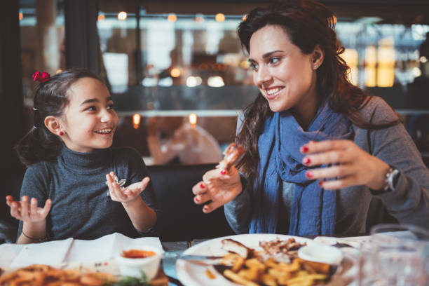 istock Mother with little daughter eating dinner in restaurant 1038961416