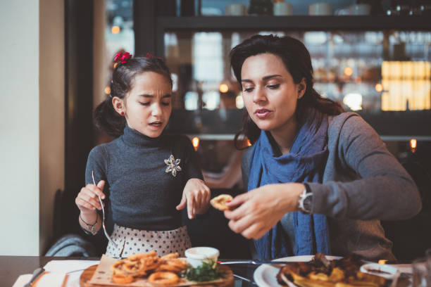 istock Mother with daughter eating in restaurant at dinner 1038961580