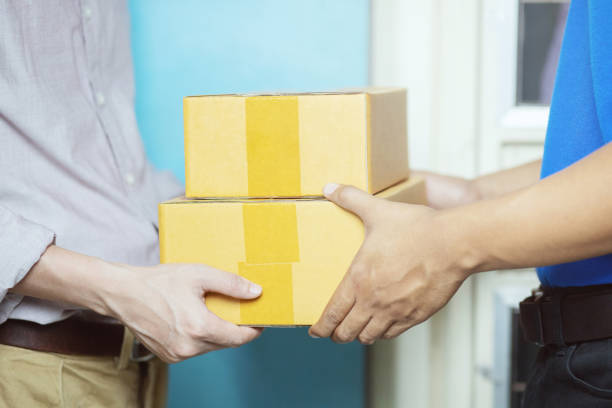 istock parcel delivery man of a package through a service. and close up hand customer accepting a delivery of boxes from delivery man postal send direct to home. Payment money by credit card. 1038971034