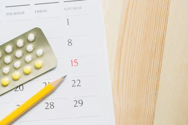 Photo of Contraceptive control pills and condom on date of calendar calculate date Control the birth rate. table wood background. health care and medicine, contraception concept. empty space for text.