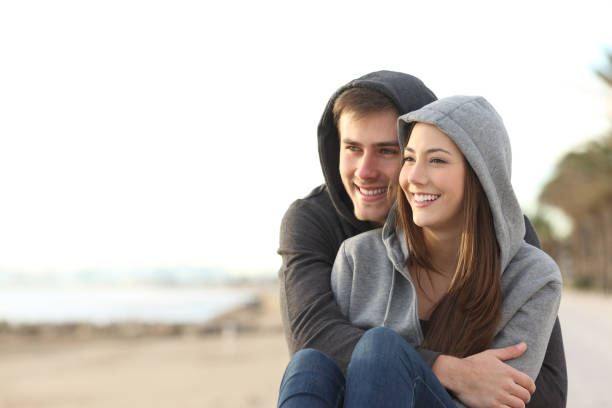 paar teens blick auf horizont am strand - teenage couple stock-fotos und bilder