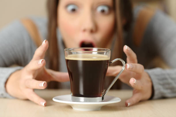Amazed woman looking at coffee cup Front view portrait of an amazed woman looking at coffee cup caffeine stock pictures, royalty-free photos & images