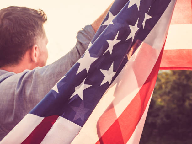istock Attractive man holding waving in the wind US flag 1039046850