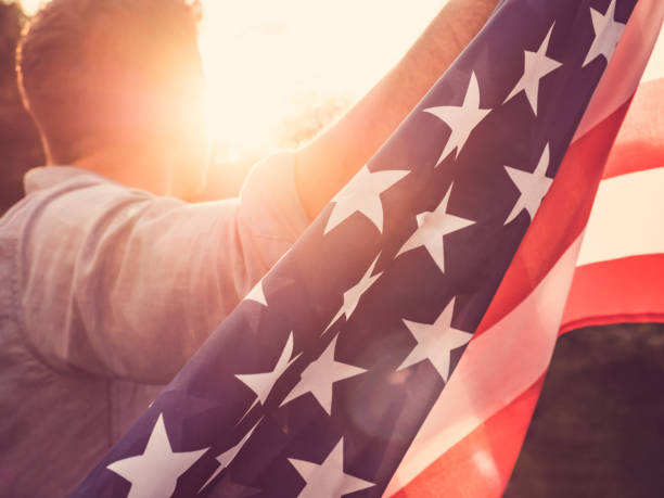 istock Attractive man holding waving in the wind US flag 1039046904