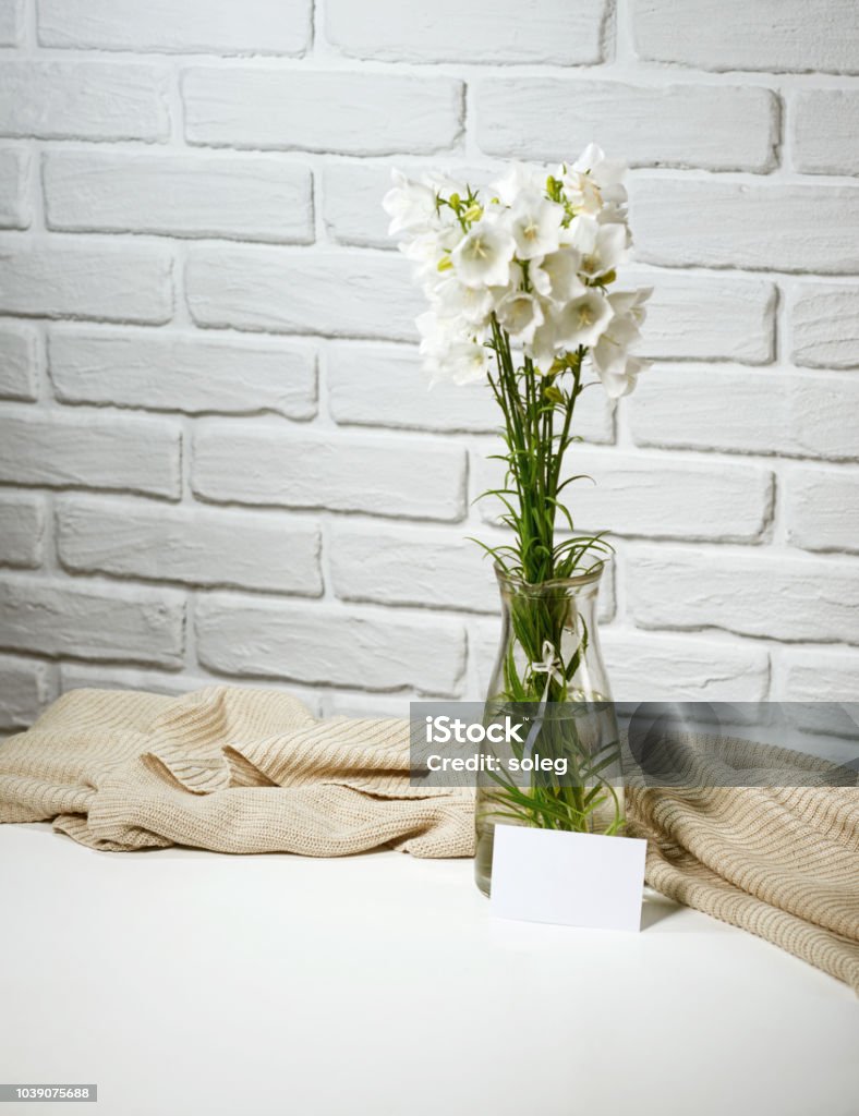 Flores Blancas En Un Florero Está Sobre La Mesa Con Hacer Punto De Lana Fondo De Pared De Ladrillo Papel En Blanco Para El Mensaje Foto de stock y más banco de Flores Blancas En Un Florero Está Sobre La Mesa Con Hacer Punto De Lana Fondo De Pared De Ladrillo Papel En Blanco Para El Mensaje Foto de stock y más banco de